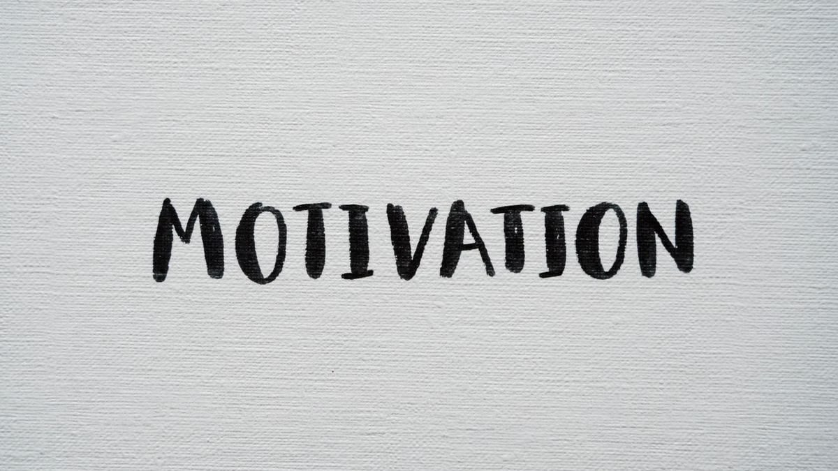 Inspirational word 'Motivation' in black on a white textured canvas background.